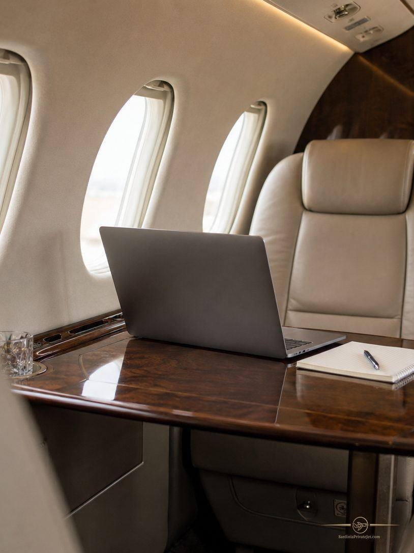 Private jet cabin seen from the aisle, leather seats and side tables